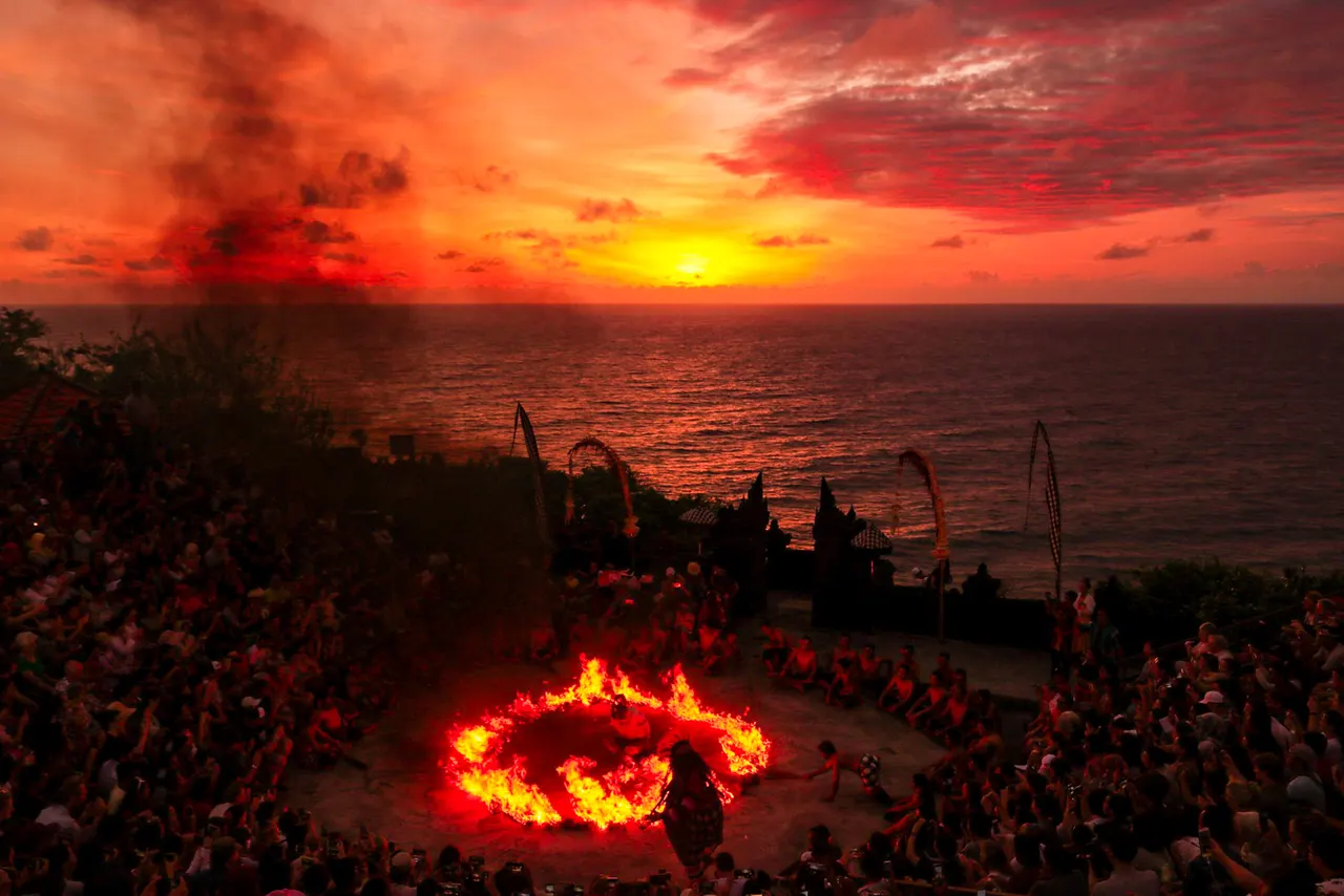 Kecak fire dance in a clifftop amphitheatre in Bali, a ring of fire burning as the sun sets over the sea.