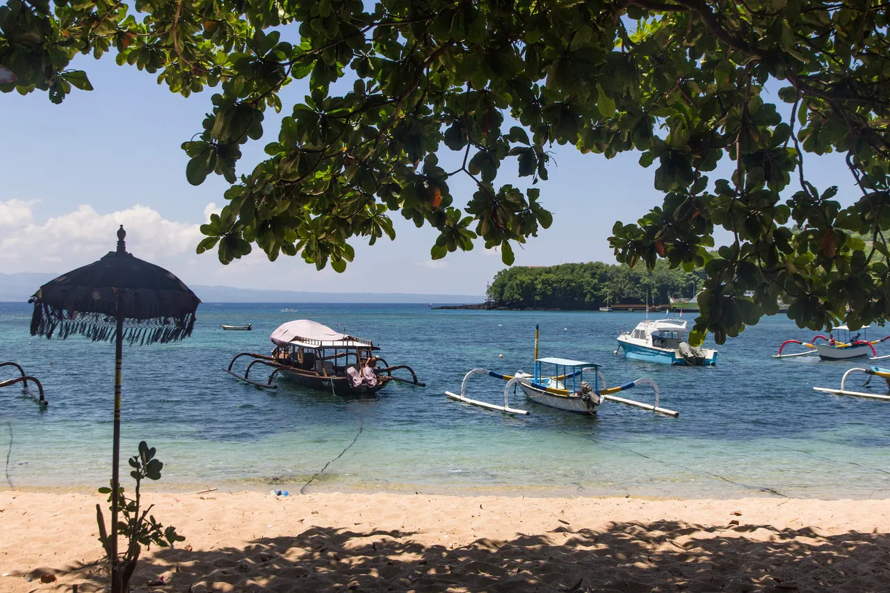 Traditional outrigger boats moored in clear shallow water off the main beach at Padangbai, east Bali.