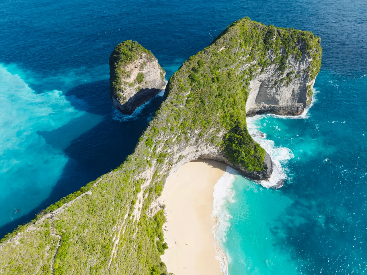 Aerial view of the dinosaur-shaped Kelingking Beach headland and turquoise bay on Nusa Penida, Bali.