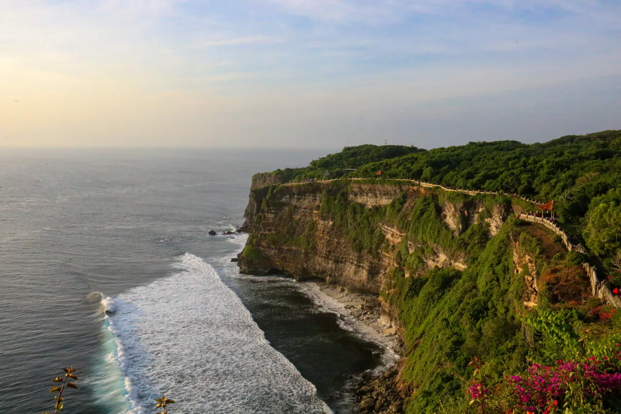 Limestone cliffs and the Indian Ocean seen from the clifftop at Uluwatu temple, Bali, in warm low light.