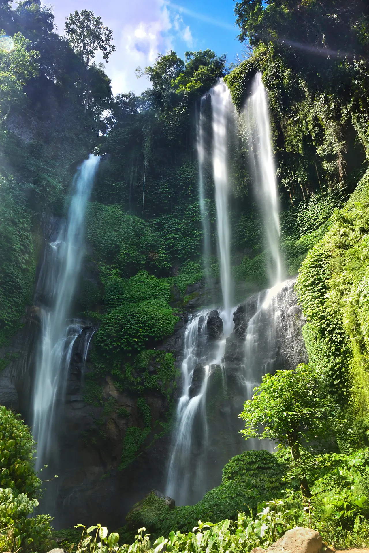 Tall twin falls of Sekumpul Waterfall dropping through dense green jungle in Buleleng, north Bali.