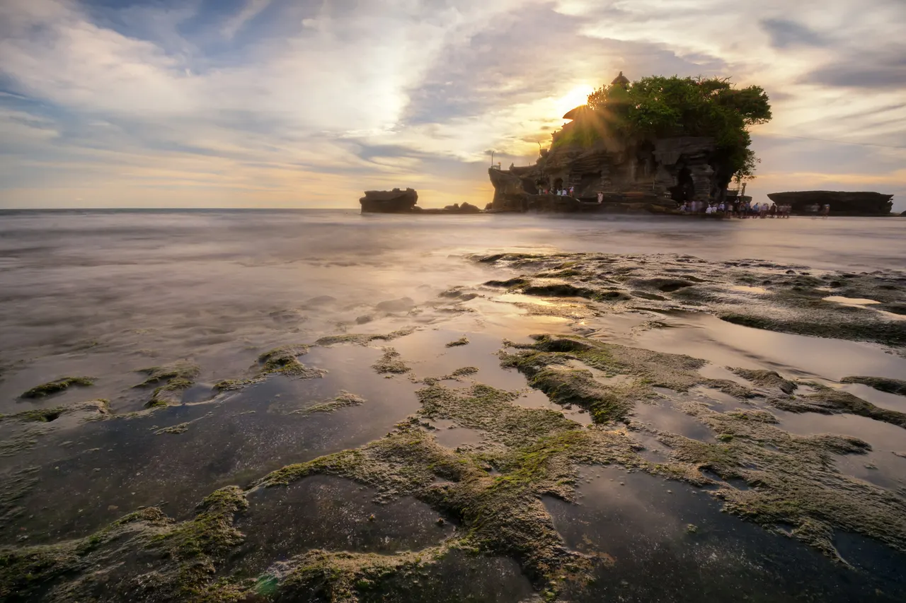Sun rays over the sea temple Pura Tanah Lot on the west coast of Bali at sunset.